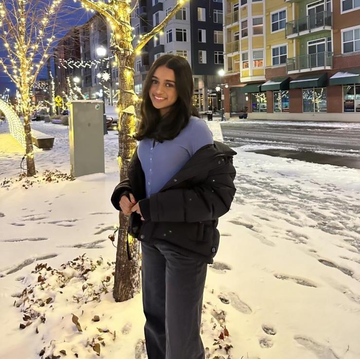 student Vibha Narasayya poses in front of a tree with snow on the ground